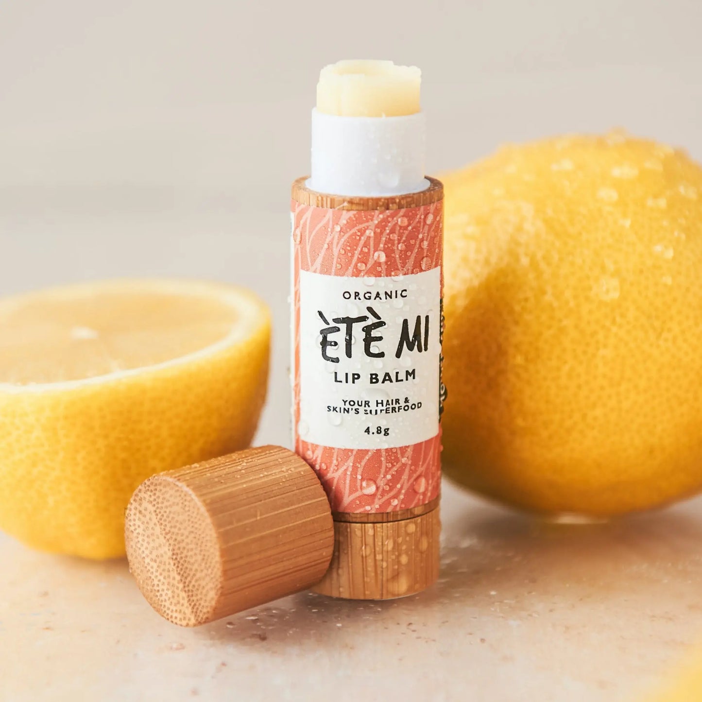 Organic lip balm in eco-friendly packaging with bamboo cap, shown with fresh lemons. Moisturising lip balm for dry lips, made with natural ingredients for soft, hydrated lips.