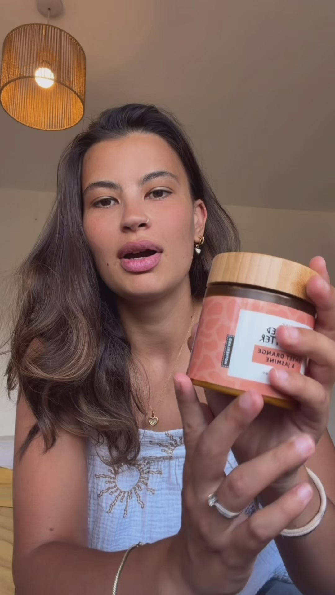 Woman applying raw unrefined shea butter with sweet orange and jasmine to her skin and hair from a Motherland amber jar