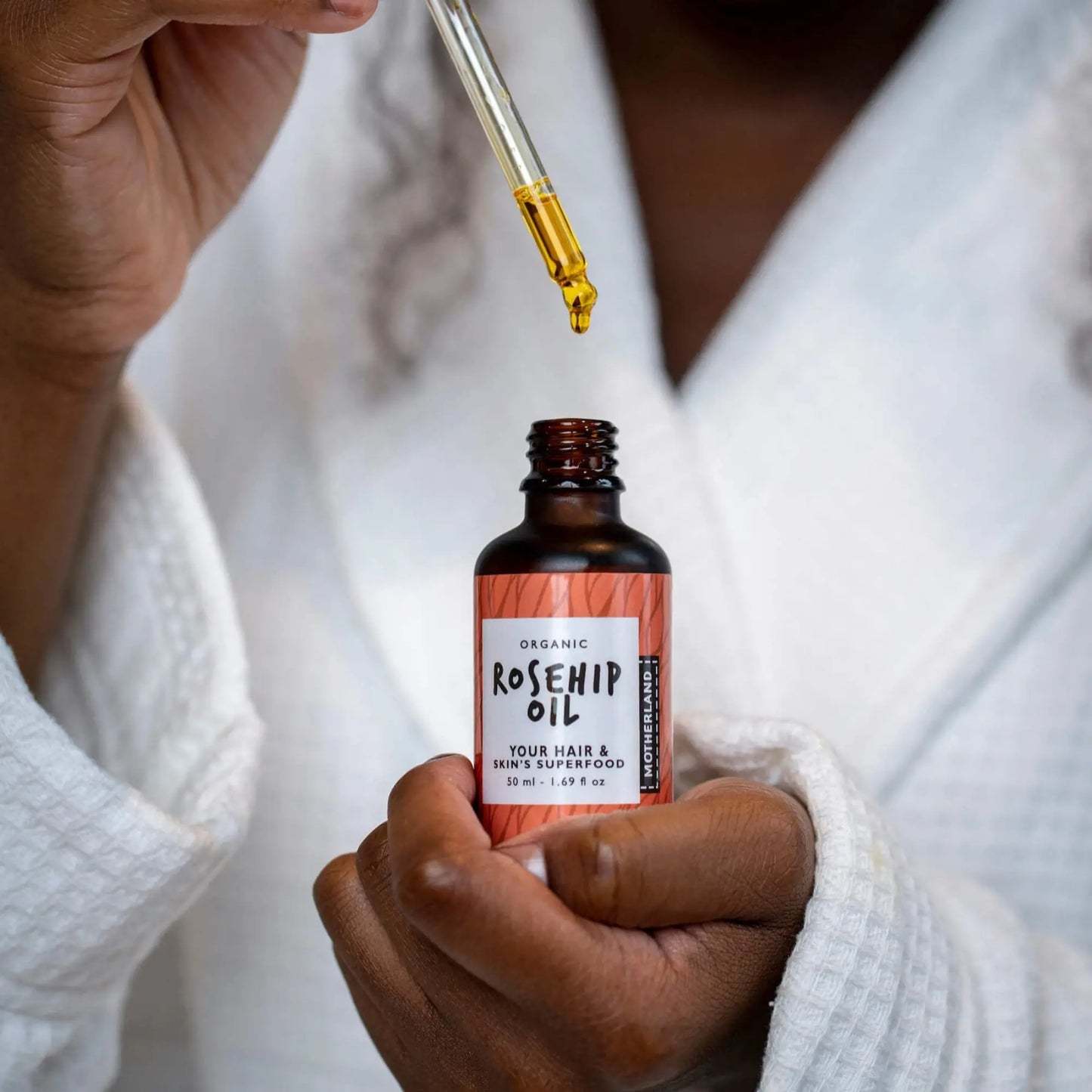 Organic rosehip oil being dispensed from dropper bottle onto skin, rich in vitamins A and C — ideal for face, scars, hyperpigmentation, and natural skincare routines.